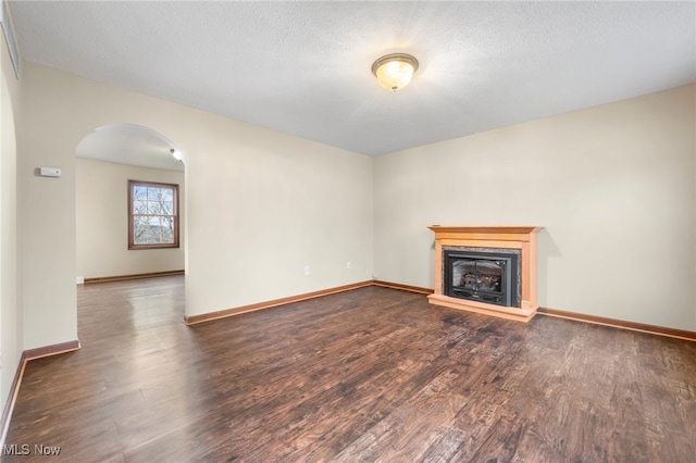 unfurnished living room featuring dark wood-type flooring and a textured ceiling