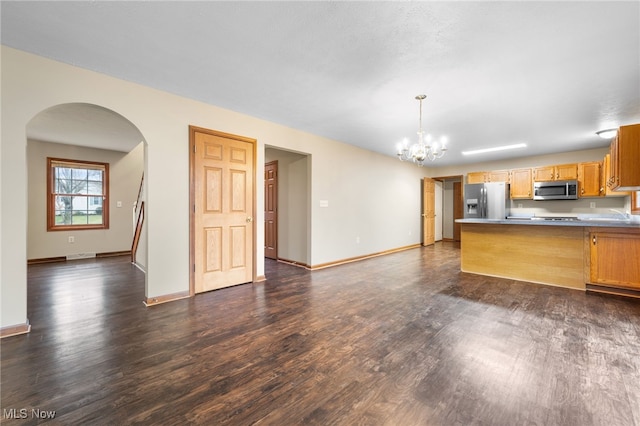 kitchen featuring kitchen peninsula, appliances with stainless steel finishes, decorative light fixtures, a notable chandelier, and dark hardwood / wood-style floors