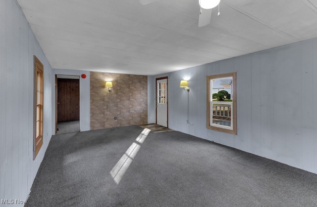 spare room featuring carpet floors, ceiling fan, and wooden walls