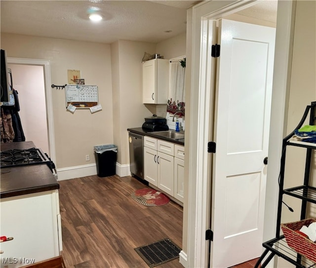 kitchen featuring white cabinets, gas range, stainless steel dishwasher, dark hardwood / wood-style floors, and a textured ceiling