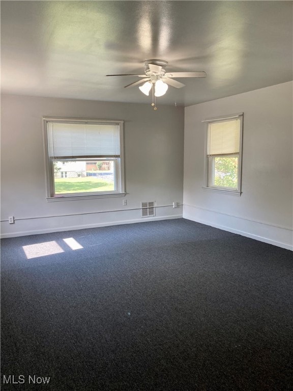 empty room with dark colored carpet and ceiling fan