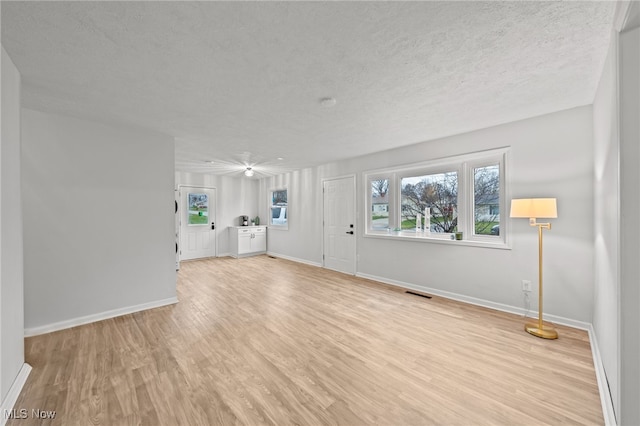 unfurnished living room with a textured ceiling and light hardwood / wood-style floors