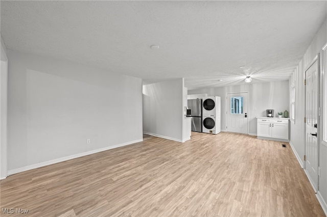 interior space with a textured ceiling, light hardwood / wood-style flooring, and stacked washer and clothes dryer