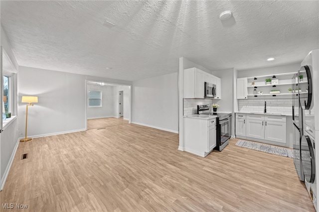 kitchen featuring a textured ceiling, light wood-type flooring, white cabinetry, and stainless steel appliances