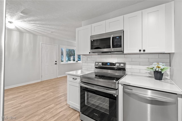 kitchen featuring tasteful backsplash, light hardwood / wood-style flooring, a textured ceiling, white cabinets, and appliances with stainless steel finishes