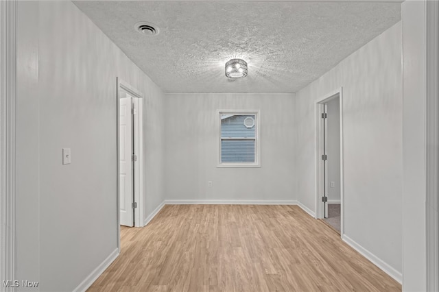 spare room featuring a textured ceiling and light wood-type flooring