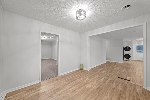 interior space with stacked washing maching and dryer, a textured ceiling, and light hardwood / wood-style floors