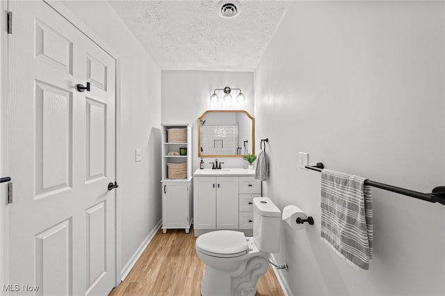 bathroom with hardwood / wood-style floors, vanity, toilet, and a textured ceiling