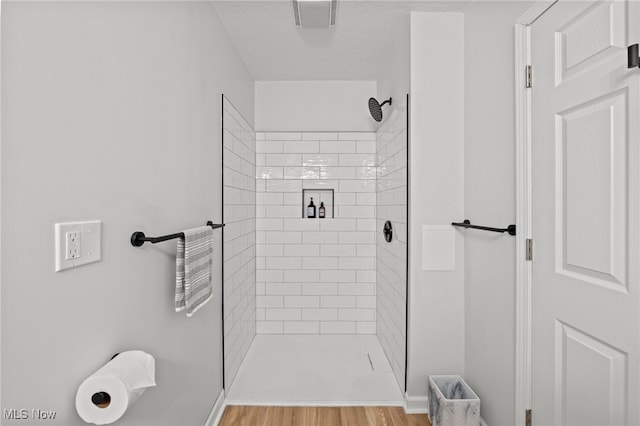 bathroom with tiled shower, hardwood / wood-style floors, and a textured ceiling