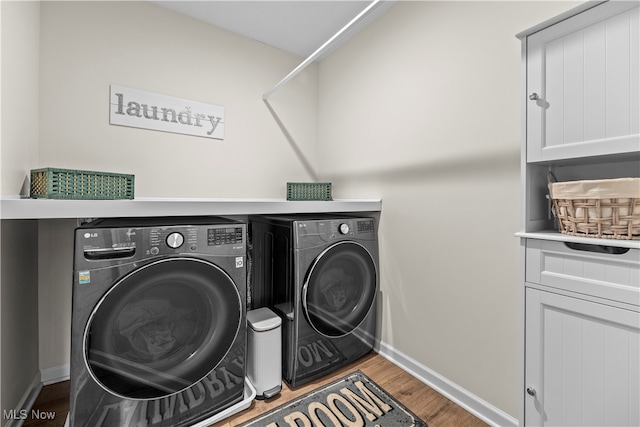 laundry room with washer and clothes dryer, cabinets, and wood-type flooring