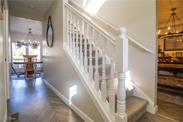 staircase featuring parquet flooring and a chandelier