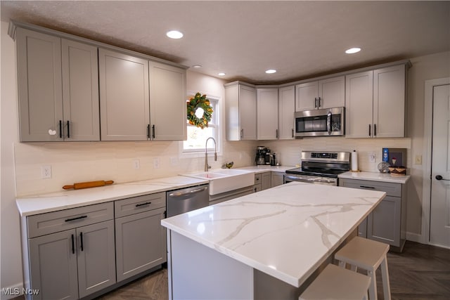 kitchen featuring gray cabinetry, sink, stainless steel appliances, light stone counters, and dark parquet floors