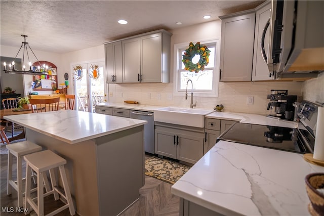 kitchen with an inviting chandelier, stainless steel appliances, a kitchen island, and a healthy amount of sunlight