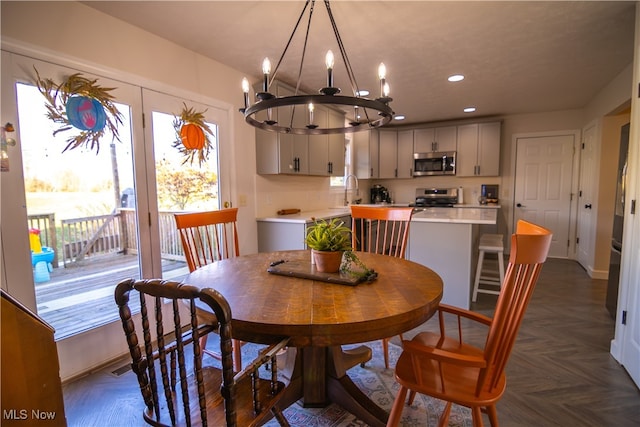 dining space featuring dark parquet flooring, sink, and an inviting chandelier