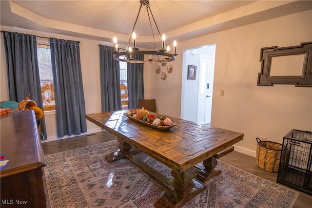 dining room with dark parquet floors, a tray ceiling, and a notable chandelier