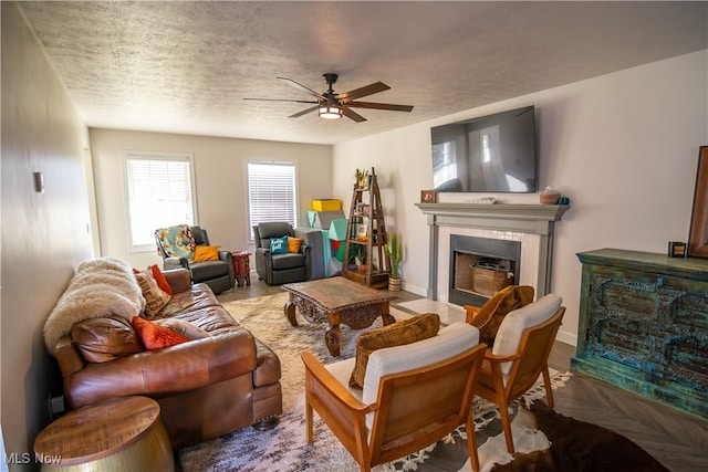 living room featuring a tile fireplace, a textured ceiling, ceiling fan, and parquet flooring