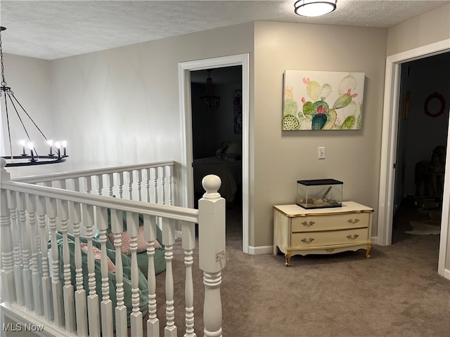 carpeted bedroom with a chandelier, a textured ceiling, and a nursery area