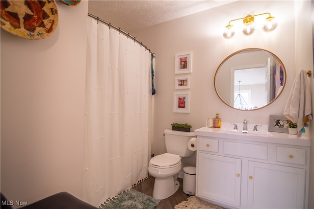 bathroom with hardwood / wood-style floors, vanity, toilet, and a textured ceiling