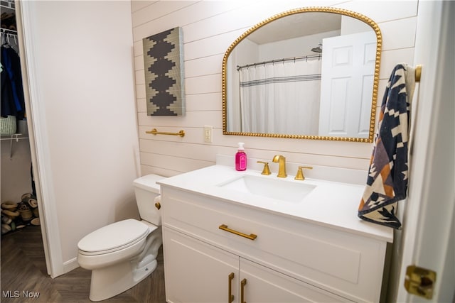 bathroom featuring curtained shower, parquet floors, wood walls, toilet, and vanity