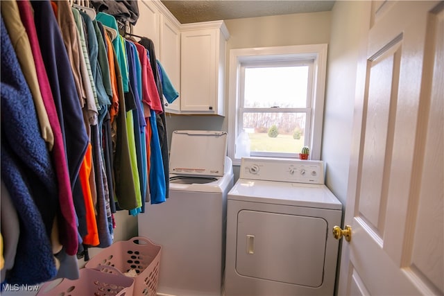 washroom with cabinets, a textured ceiling, and washing machine and clothes dryer