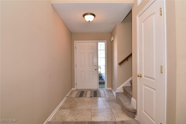 foyer with light tile patterned floors, stairway, and baseboards