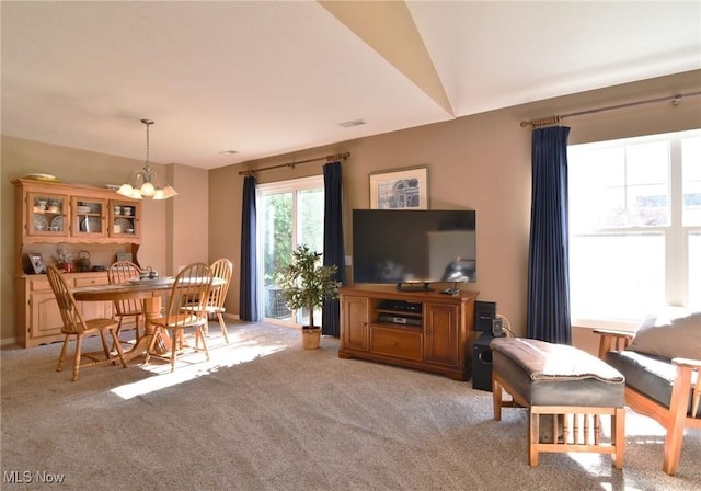 living room with lofted ceiling, light carpet, and a chandelier