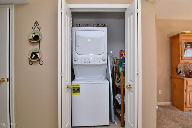 washroom featuring stacked washer and clothes dryer and light carpet