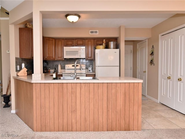 kitchen with sink, decorative backsplash, kitchen peninsula, light carpet, and white appliances