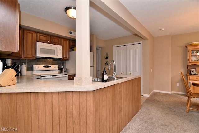 kitchen with tasteful backsplash, sink, kitchen peninsula, light carpet, and white appliances