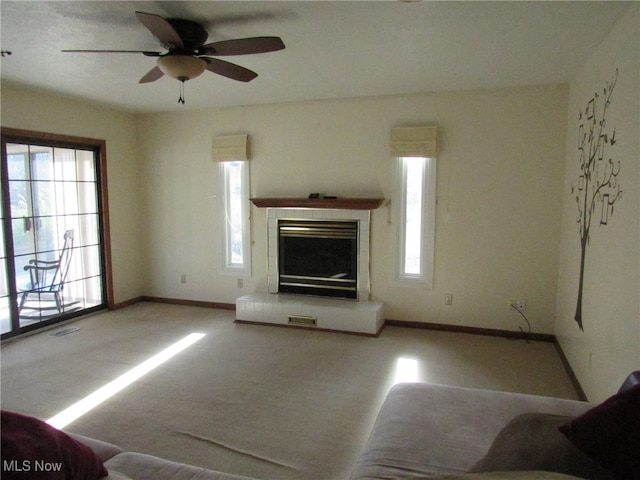 unfurnished living room featuring ceiling fan, light colored carpet, and a wealth of natural light