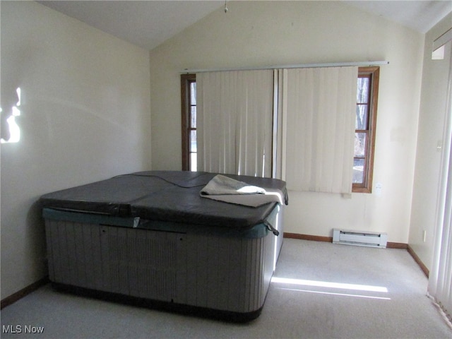 unfurnished bedroom featuring light colored carpet, a baseboard radiator, and vaulted ceiling