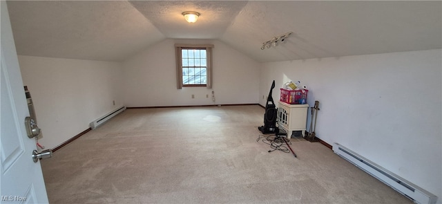 additional living space featuring light carpet, a textured ceiling, vaulted ceiling, and a baseboard heating unit