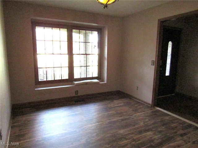 spare room with plenty of natural light and dark hardwood / wood-style floors