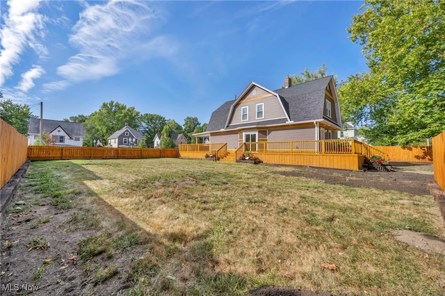 rear view of house featuring a yard and a deck