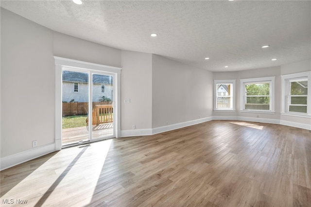 spare room with a textured ceiling and light hardwood / wood-style flooring