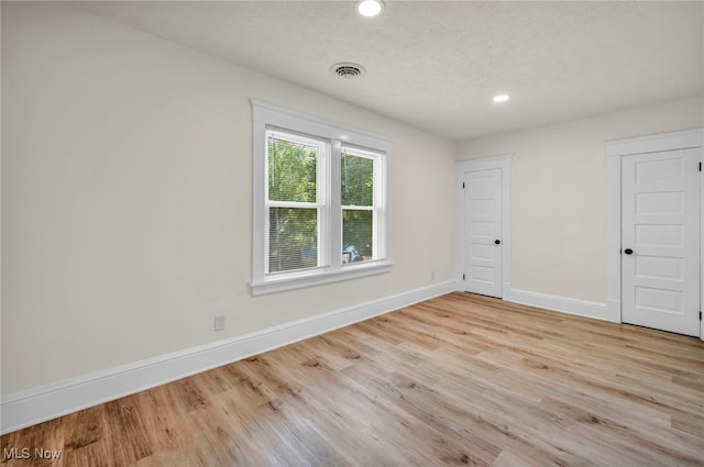 unfurnished room featuring light hardwood / wood-style floors and a textured ceiling