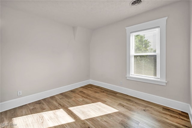 spare room featuring light hardwood / wood-style floors and a textured ceiling