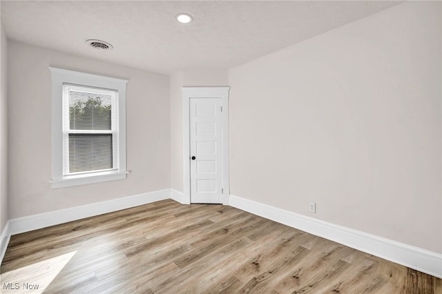 spare room with a textured ceiling and light hardwood / wood-style flooring