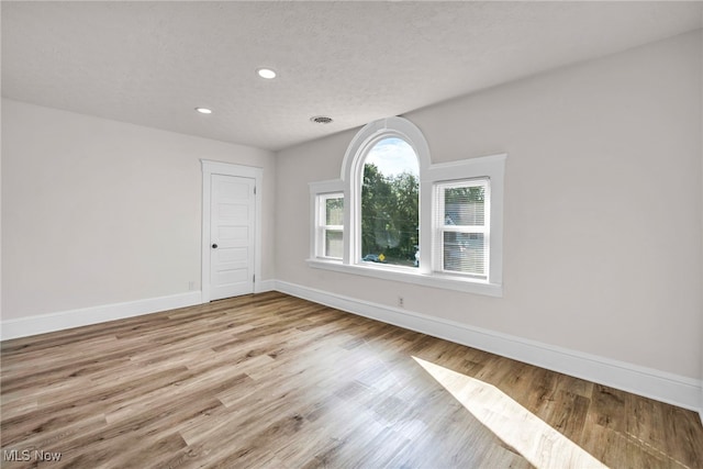 empty room with light hardwood / wood-style floors and a textured ceiling