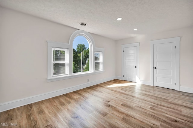 empty room featuring a textured ceiling and light wood-type flooring