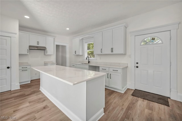 kitchen featuring white cabinets, a kitchen island, light wood-type flooring, and a textured ceiling