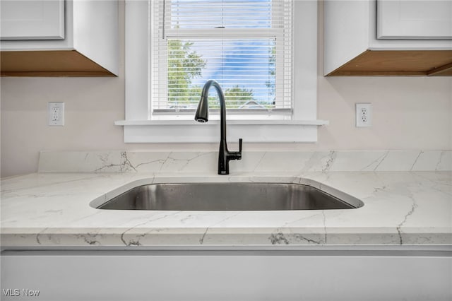 details featuring white cabinets, light stone countertops, and sink