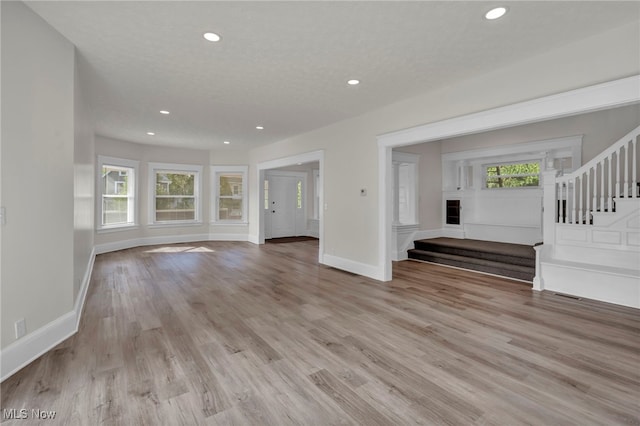 unfurnished living room with plenty of natural light, a textured ceiling, and light hardwood / wood-style flooring