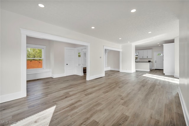 unfurnished living room featuring a textured ceiling and light wood-type flooring