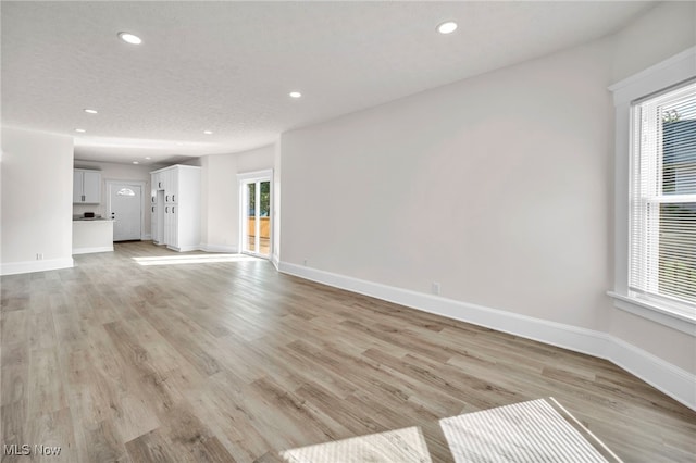 unfurnished living room with light hardwood / wood-style flooring and a textured ceiling