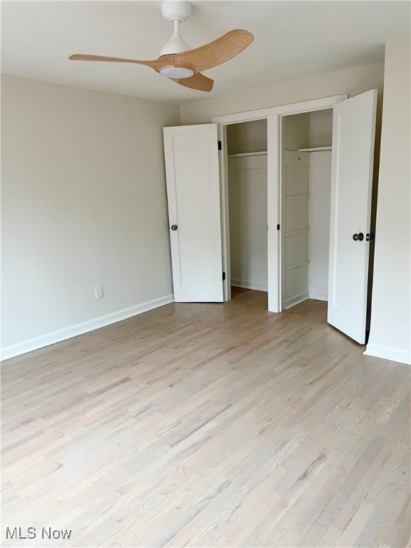 unfurnished bedroom with ceiling fan, light hardwood / wood-style floors, and multiple closets