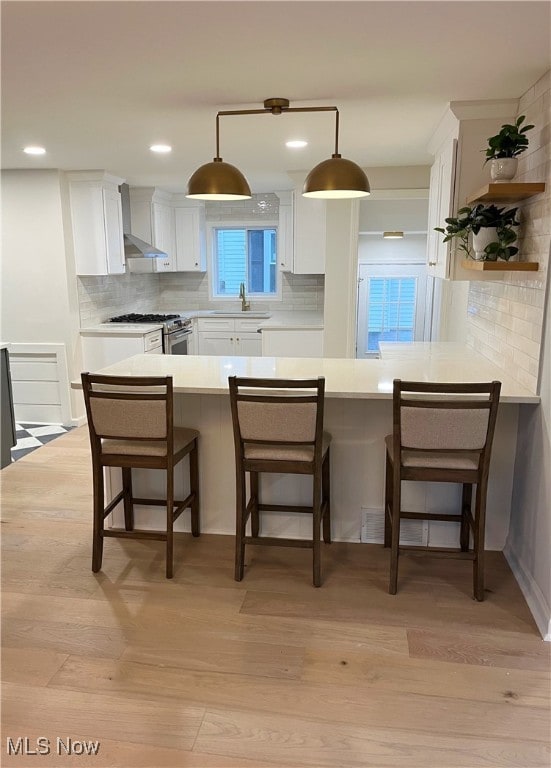 kitchen featuring a breakfast bar area, kitchen peninsula, and light hardwood / wood-style flooring