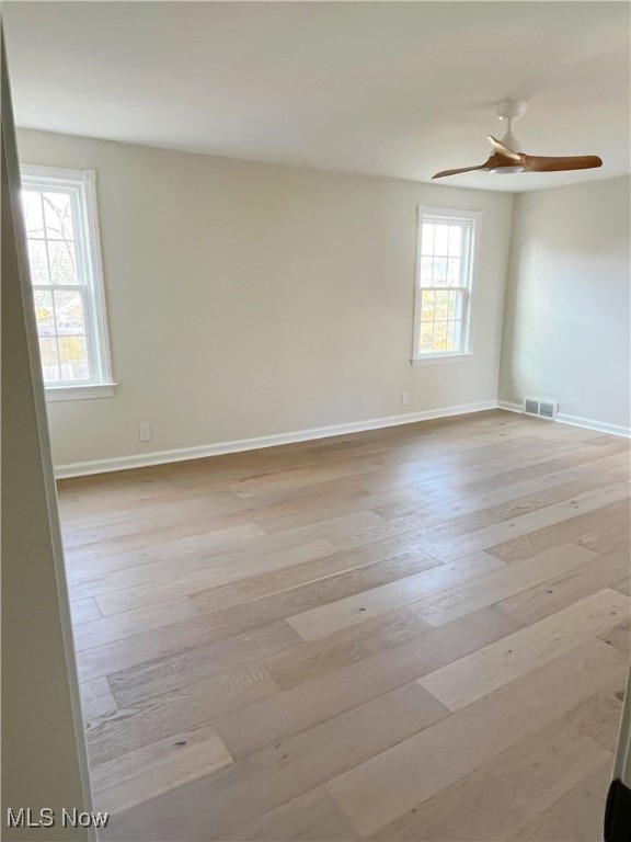 spare room featuring light hardwood / wood-style floors, ceiling fan, and a healthy amount of sunlight