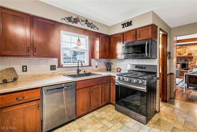 kitchen featuring a stone fireplace, decorative backsplash, sink, and stainless steel appliances