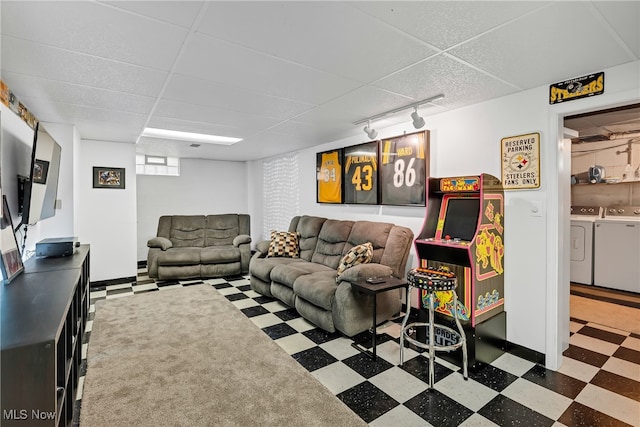 living room with washer and dryer, rail lighting, and a drop ceiling